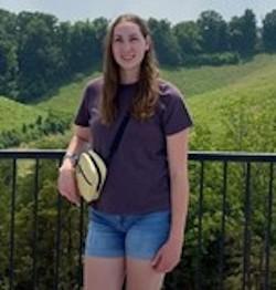 Female student leaning against a fence