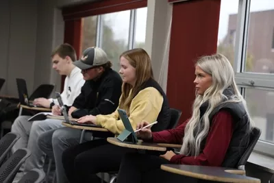 Four students sitting at desks in a classroom