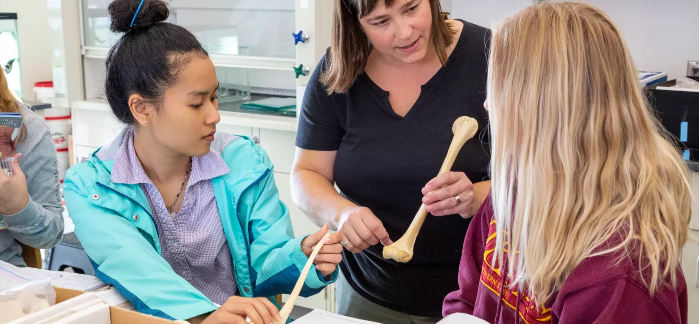 Faculty showing a skeleton to two female students